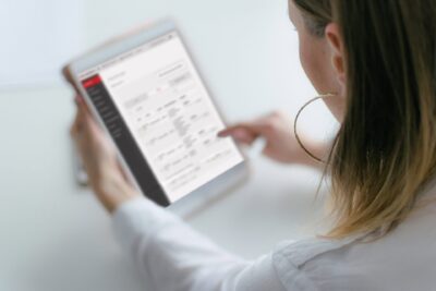 Eine Frau nutzt ein Tablet, um eine medizinische oder apothekenbezogene Anwendung zu überprüfen, mit Fokus auf Operationen und Gesundheitsdienstleistungen.